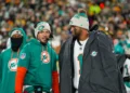 Quarterback Tua Tagovailoa #1 of the Miami Dolphins and head coach Mike McDaniel of the Miami Dolphins stand on the sidelines prior to an NFL football game against the Green Bay Packers, at Lambeau Field in Green Bay, Wisconsin.
