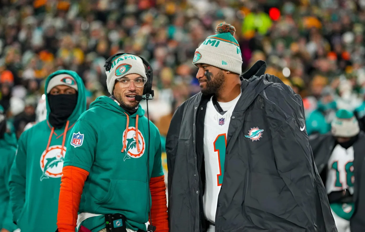 Quarterback Tua Tagovailoa #1 of the Miami Dolphins and head coach Mike McDaniel of the Miami Dolphins stand on the sidelines prior to an NFL football game against the Green Bay Packers, at Lambeau Field in Green Bay, Wisconsin.
