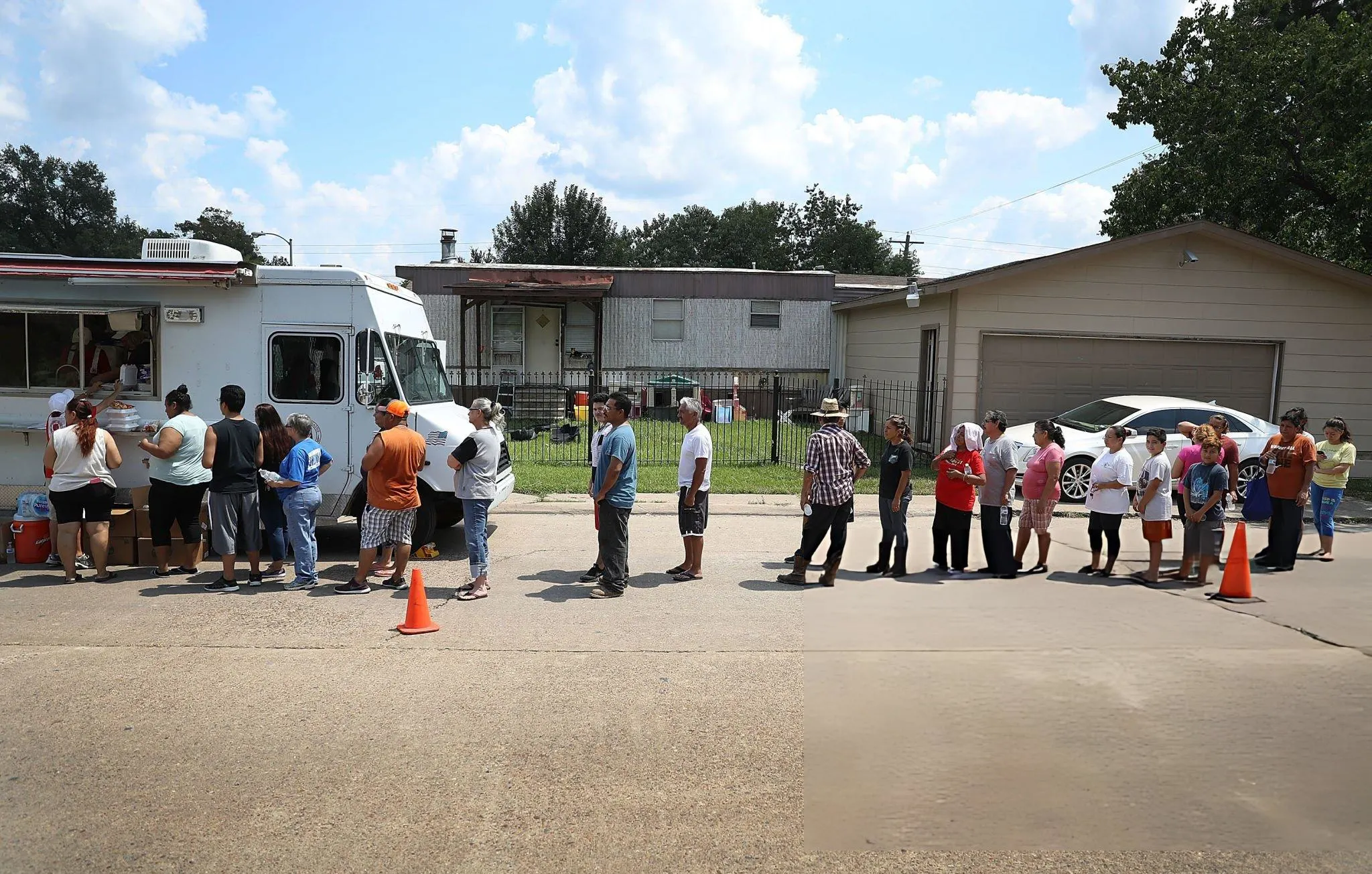 People line up to receive food and water from a Salvation Army truck after their homes were inundated with flood waters during Hurricane and Tropical Storm Harvey on September 2, 2017 in Houston, Texas. Harvey, which made landfall north of Corpus Christi on August 25, dumped around 50 inches of rain in and around areas of Houston and Southeast Texas.
