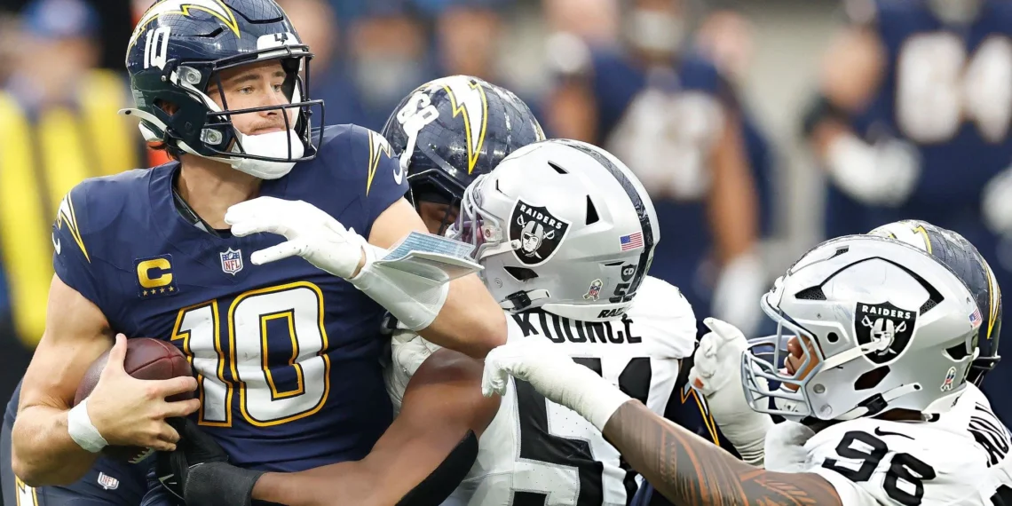 Malcolm Koonce #51 and Jonah Laulu #96 of the Las Vegas Raiders tackles Justin Herbert #10 of the Los Angeles Chargers in the third quarter of a game at SoFi Stadium on November 30, 2025 in Inglewood, California. (Photo by Ronald Martinez/Getty Images)