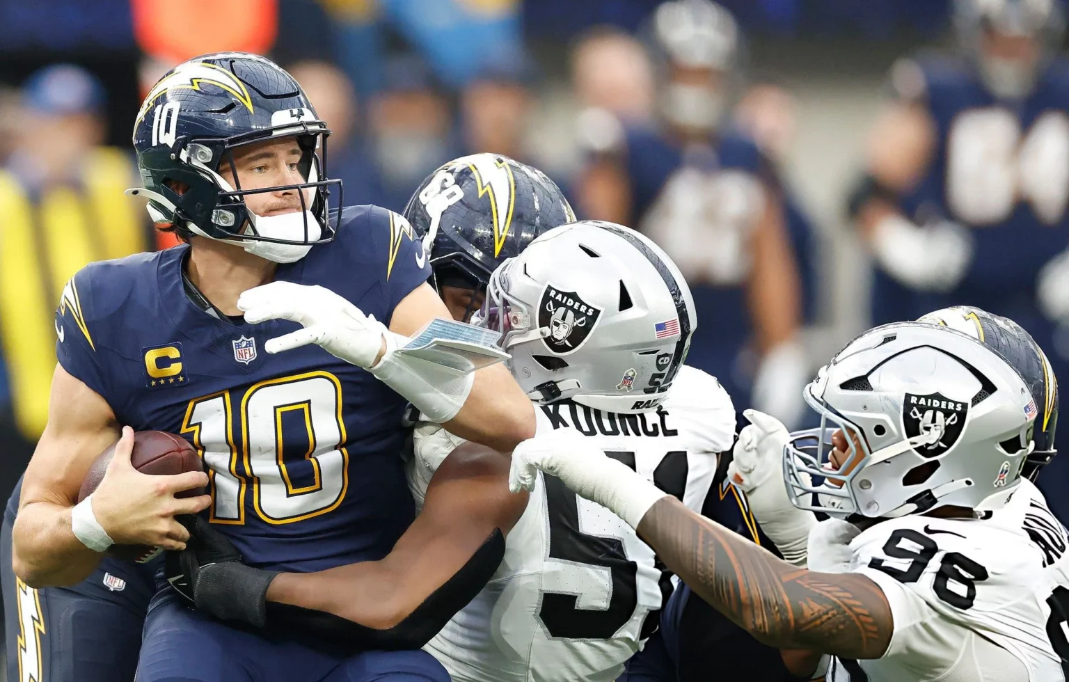 Justin Herbert Undergoes Hand Surgery After Metacarpal Fracture, Aims for Shockingly Fast Week 14 Return Malcolm Koonce #51 and Jonah Laulu #96 of the Las Vegas Raiders tackles Justin Herbert #10 of the Los Angeles Chargers in the third quarter of a game at SoFi Stadium on November 30, 2025 in Inglewood, California. (Photo by Ronald Martinez/Getty Images)