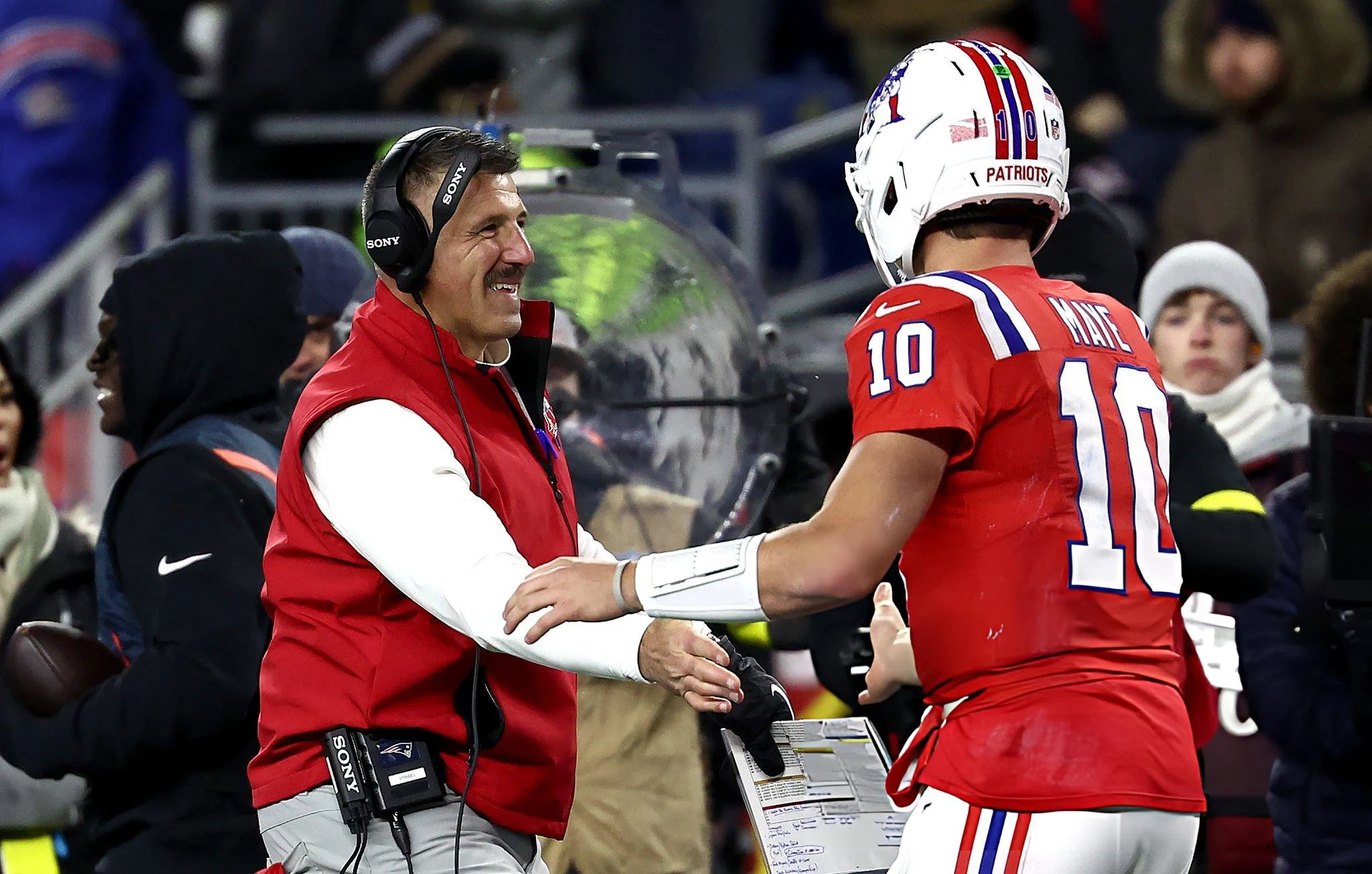 Head coach Mike Vrabel of the New England Patriots and Drake Maye #10 of the New England Patriots shake hands during the second quarter of the game against the New York Giants at Gillette Stadium